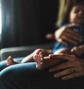 Mother's hands holding baby on lap with feet center of frame